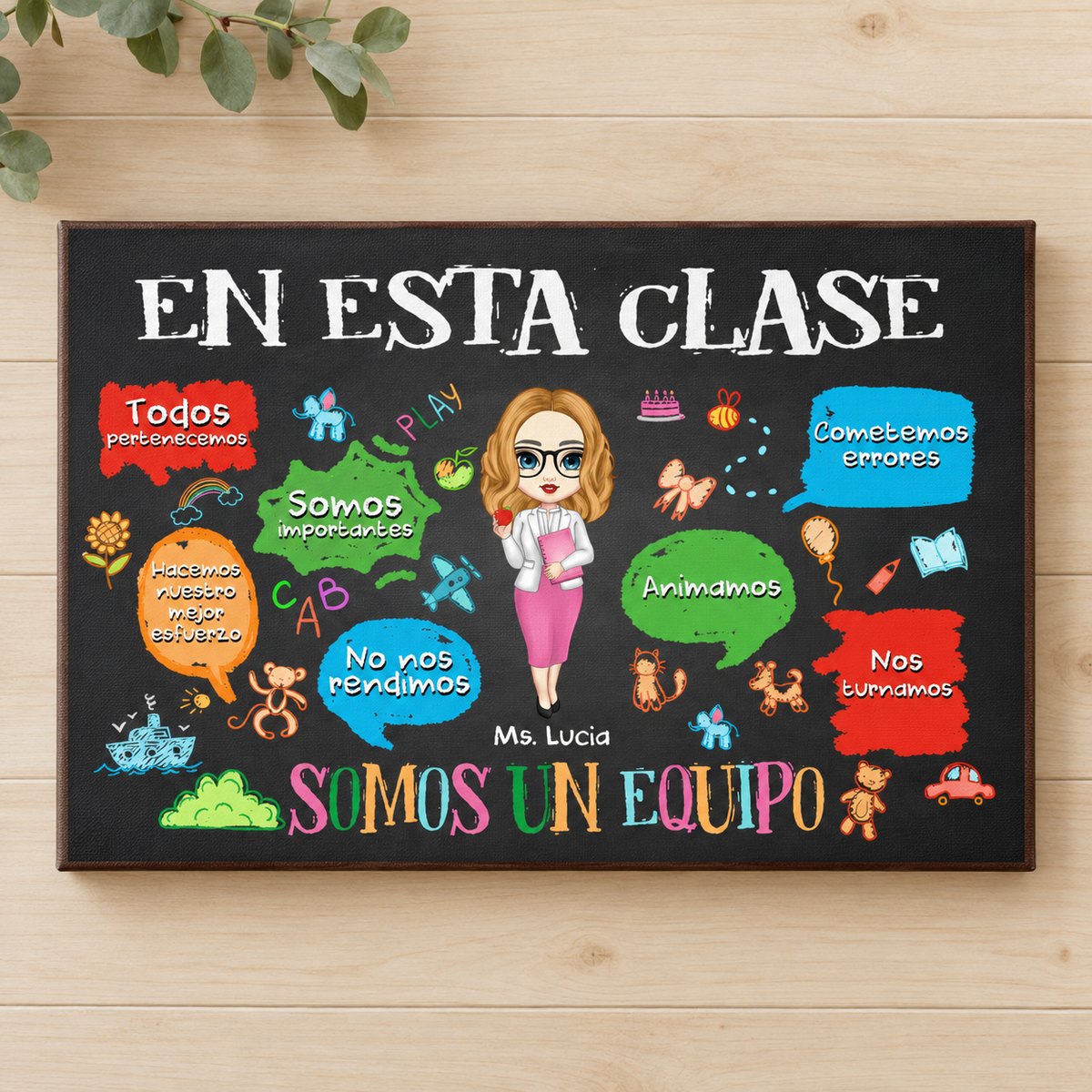 In This Classroom We Are A Team Spanish canvas displayed on a light wood wall with greenery